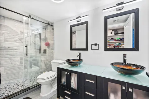a bathroom with a granite countertop sink a toilet a mirror and shower