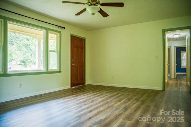 a view of empty room with wooden floor and fan