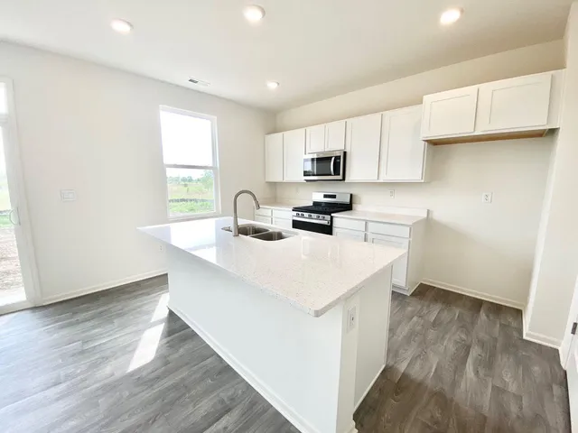 a kitchen with kitchen island a sink a stove a microwave a center island and a window