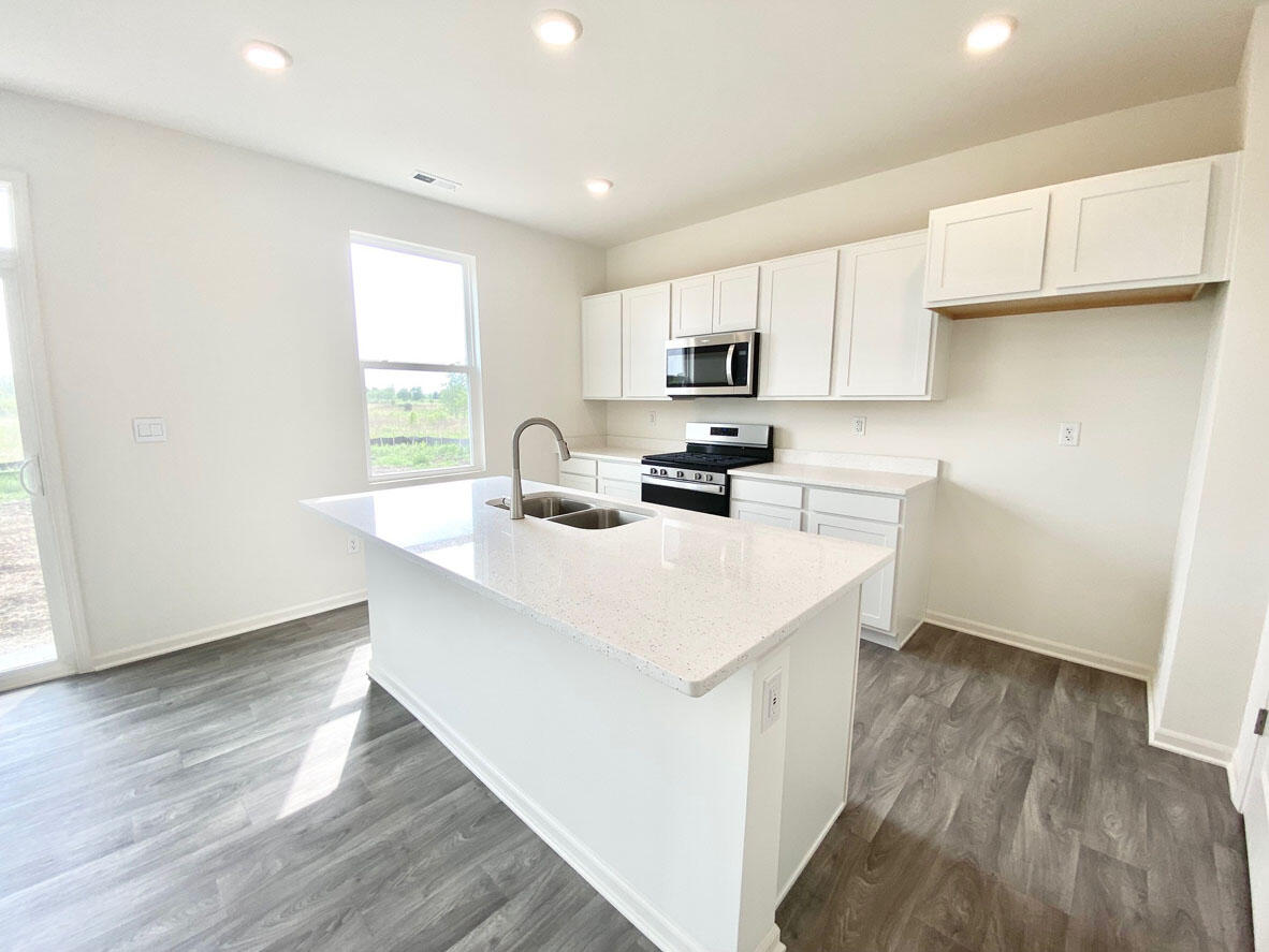 585 Marcella Street Hebron, IN 46341 - Photo 5 of 21 a kitchen with kitchen island a sink a stove a microwave a center island and a window