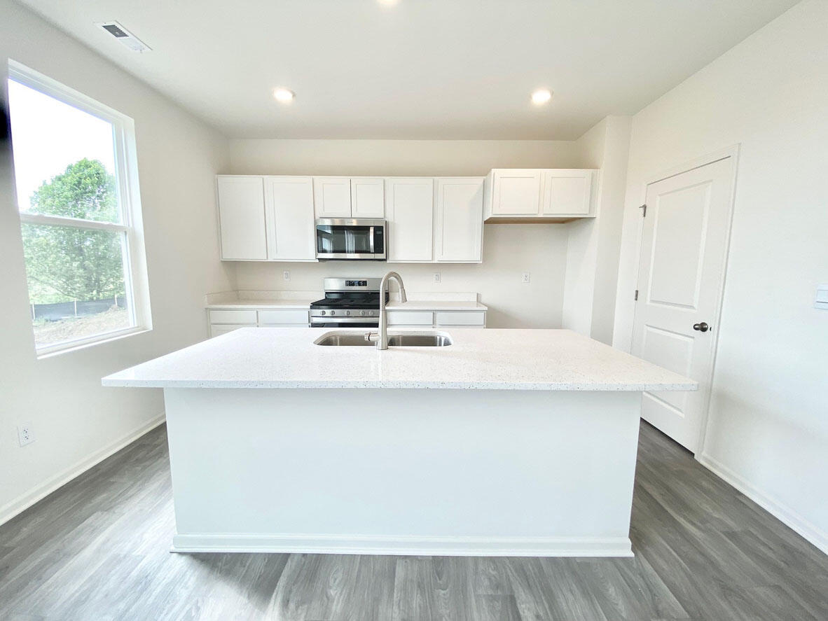585 Marcella Street Hebron, IN 46341 - Photo 10 of 21 a kitchen with kitchen island a stove a sink a refrigerator and white cabinets with wooden floor