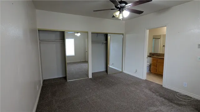 an empty room with closet and a ceiling fan