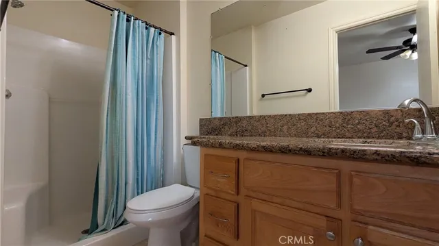 a bathroom with a granite countertop sink and a toilet