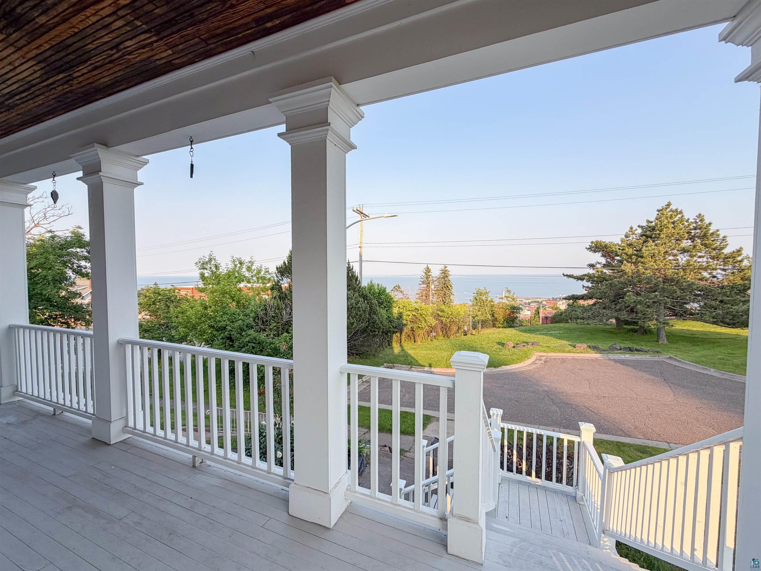 13 West 8th Street Duluth, MN 55806 - Photo 56 of 57 Spacious porch featuring white columns and railing overlooking a paved street and distant water