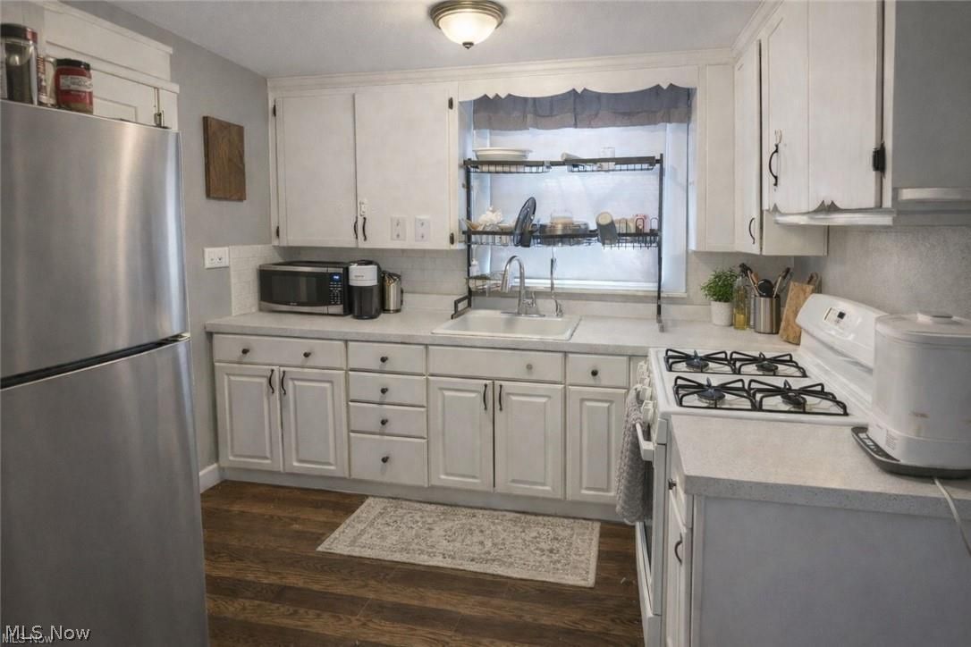1911 Youngstown Road Southeast Warren, OH 44484 - Photo 5 of 17 Kitchen with stainless steel appliances, light countertops, white cabinets, and dark wood-type flooring