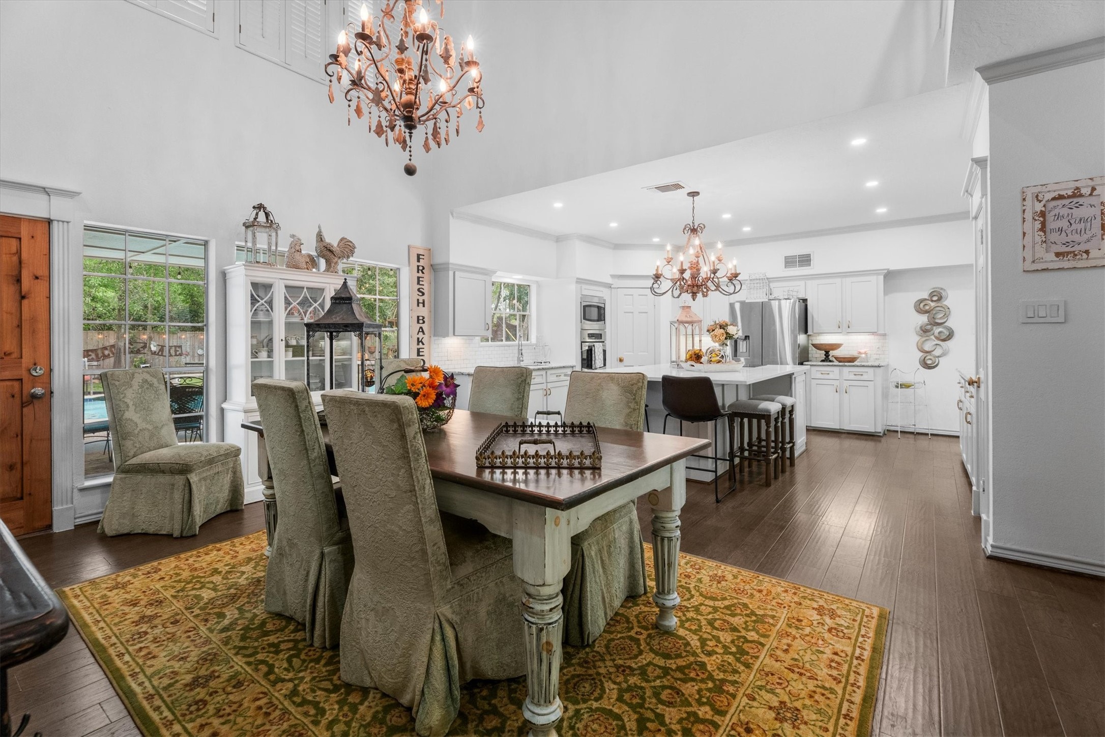 15902 Guinstead Drive Spring, TX 77379 - Photo 12 of 42 Open-concept dining and kitchen area with elegant chandeliers, hardwood floors, and a cozy, inviting atmosphere.