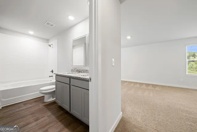 a bathroom with a granite countertop toilet a sink and a bathtub