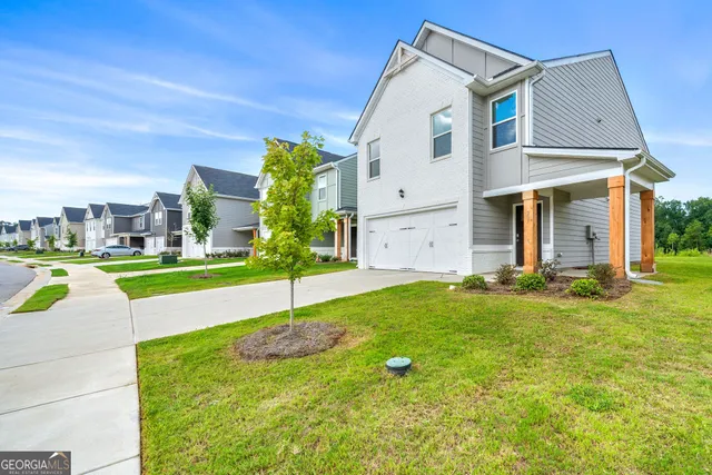 a view of a white house with a big yard and potted plants