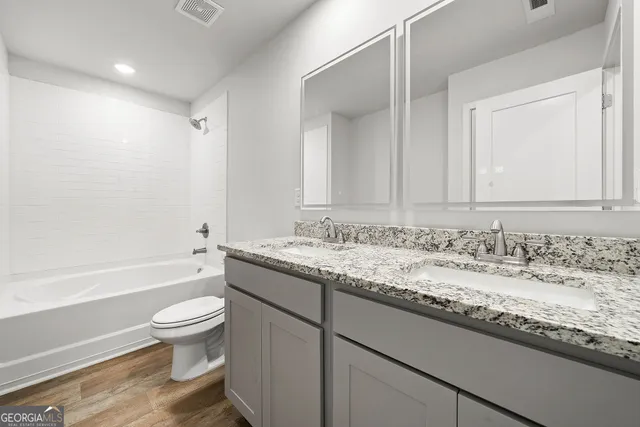 a bathroom with a granite countertop sink toilet mirror and bathtub