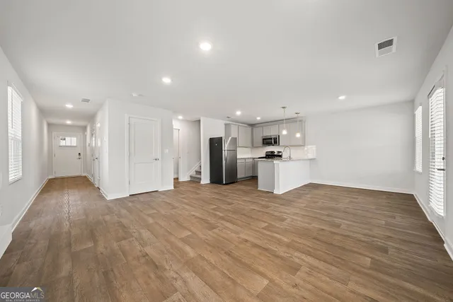 a view of kitchen with kitchen island wooden floor appliances and cabinets