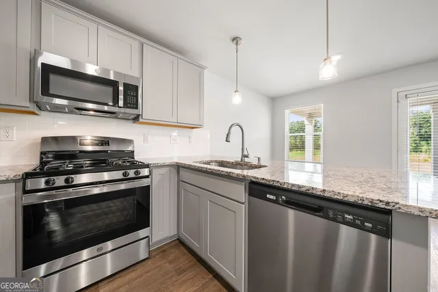 a kitchen with stainless steel appliances granite countertop a sink a stove a microwave and wooden floors