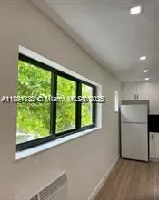 a view of an empty room with a window and kitchen view