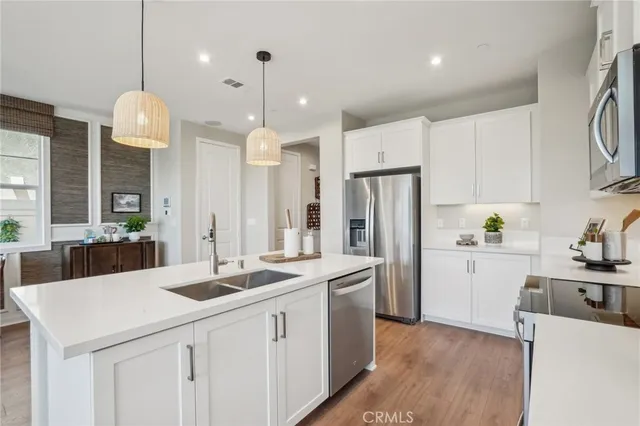 a kitchen with stainless steel appliances a stove a sink a center island and cabinets