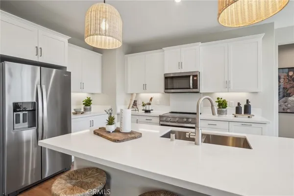 a kitchen with stainless steel appliances a stove a refrigerator a sink a stove a microwave and cabinets