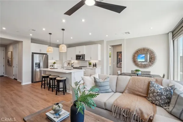 a living room with stainless steel appliances kitchen island granite countertop a couch a stove a dining table and chairs with wooden floor