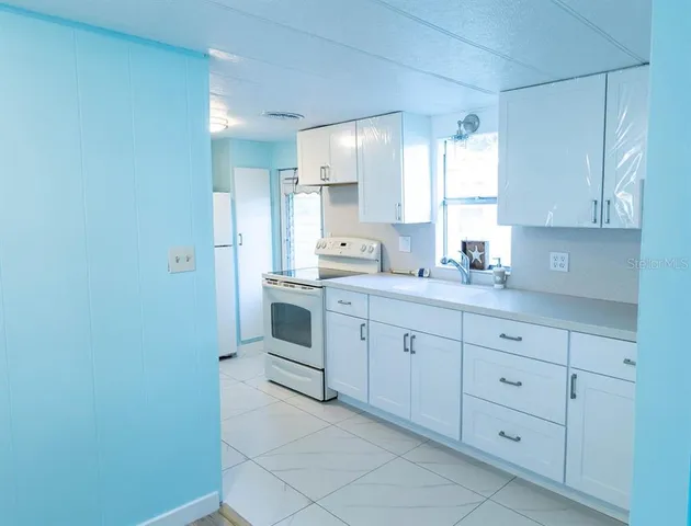 a kitchen with white cabinets and white appliances
