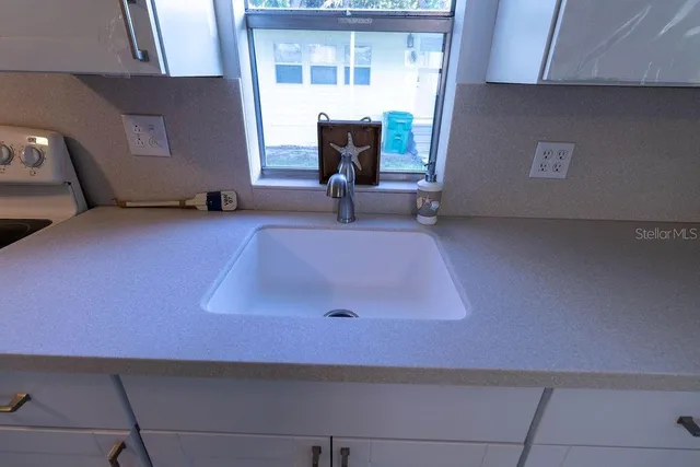 a kitchen with white cabinets and sink