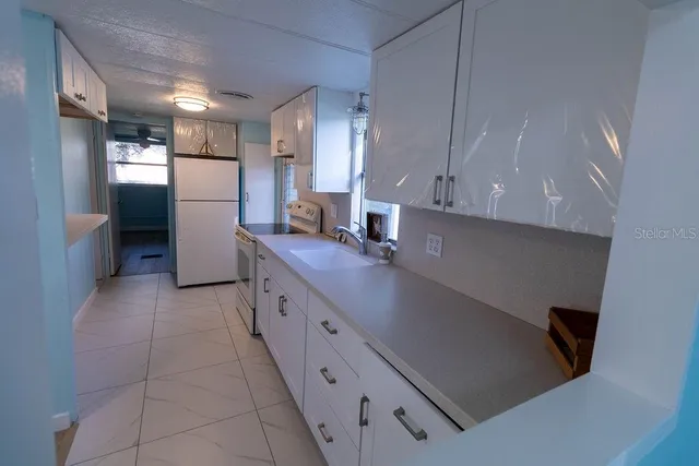 a kitchen with white cabinets and window