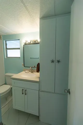 a bathroom with a granite countertop toilet sink and mirror