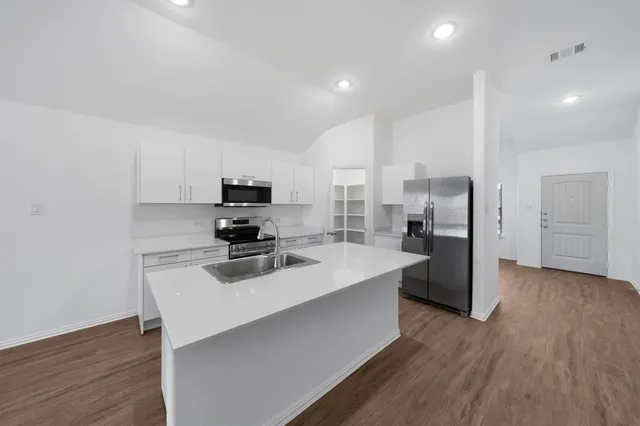 a kitchen with refrigerator cabinets and wooden floor