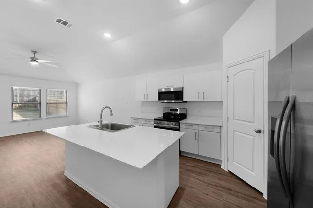 a kitchen with a sink a stove a refrigerator and cabinets