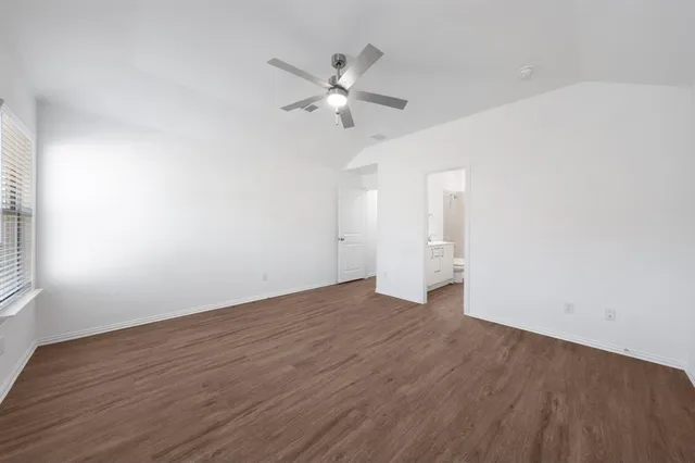 a view of an empty room with wooden floor and a ceiling fan