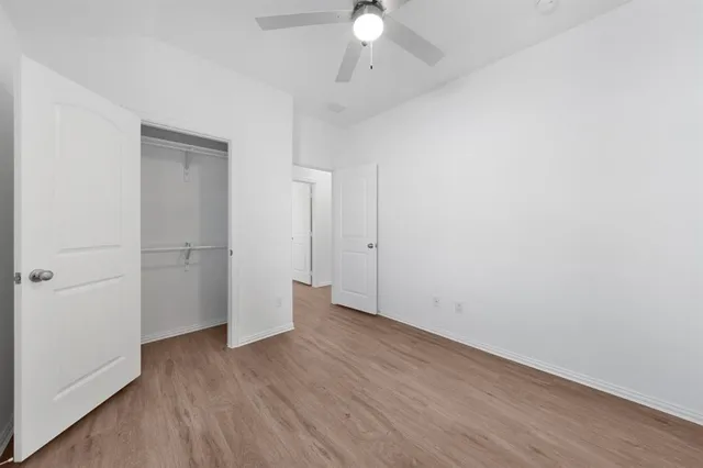 an empty room with wooden floor and a ceiling fan