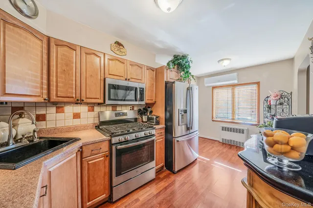 a kitchen with stainless steel appliances granite countertop a stove top oven a sink dishwasher a dining table and chairs with wooden floor