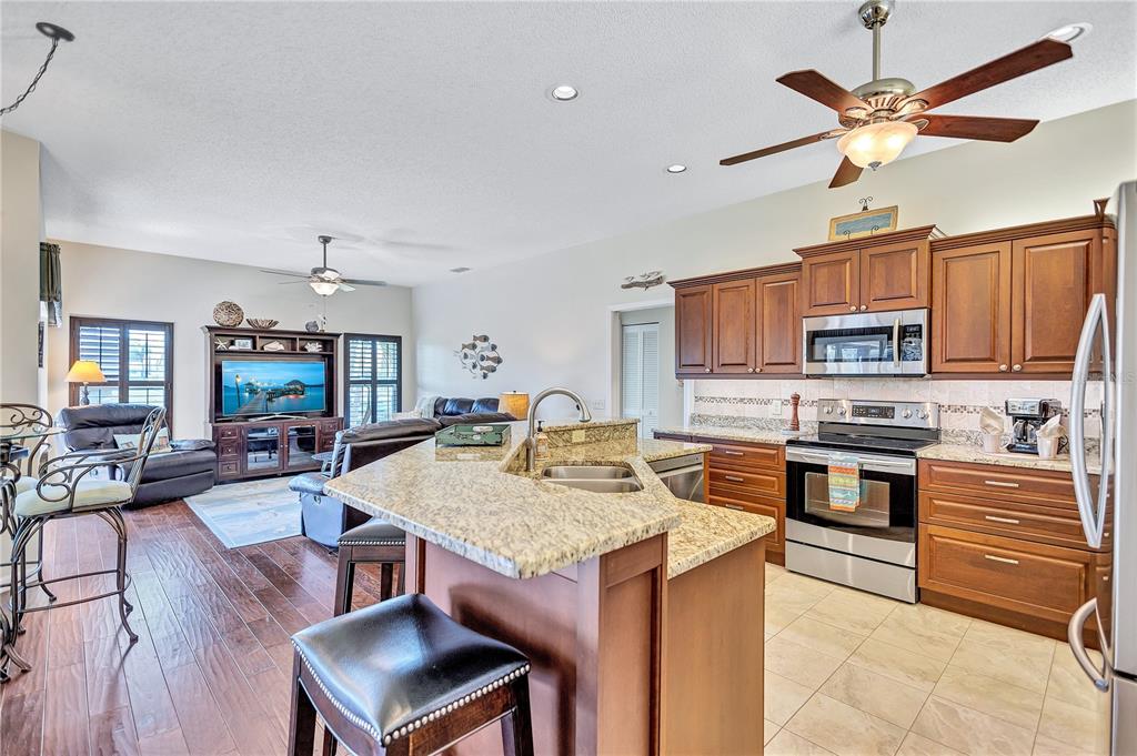 104 Inlets Boulevard, Unit 104 Nokomis, FL 34275 - Photo 19 of 66 a open kitchen with stainless steel appliances granite countertop a stove top oven a sink a dining table and chairs with wooden floor