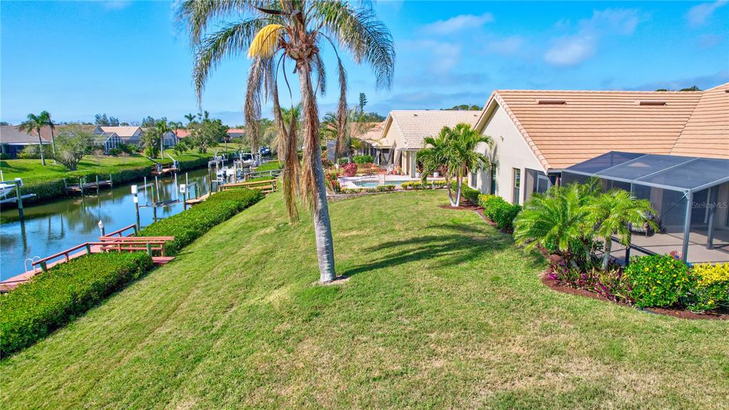 104 Inlets Boulevard, Unit 104 Nokomis, FL 34275 - Photo 60 of 66 a view of a backyard with couches under an umbrella with palm trees