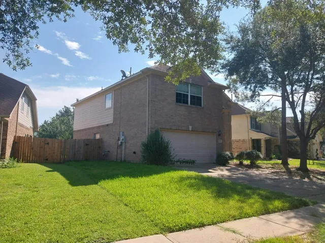 a backyard of a house with plants and large tree