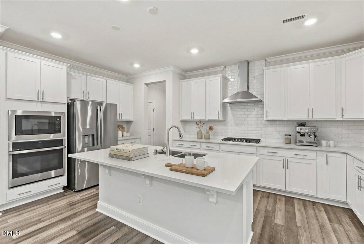 4937 Abundance Avenue Raleigh, NC 27616 - Photo 6 of 36 a kitchen with a sink a stove a refrigerator and white cabinets
