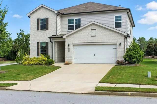 a view of a white house next to a yard and large trees