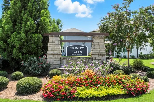 a view of sign board with plants and trees