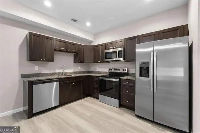 a kitchen with kitchen island granite countertop a refrigerator a sink a stove a microwave and wooden cabinets