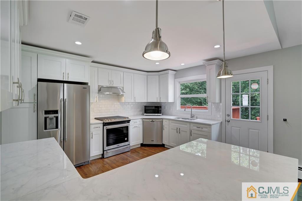 203 Riverbend Road Berkeley Heights, NJ 07922 - Photo 21 of 42 a kitchen with stainless steel appliances granite countertop a refrigerator a sink dishwasher a stove and white cabinets with wooden floor