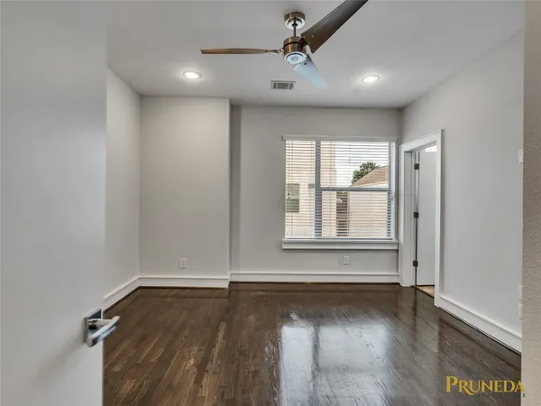 an empty room with wooden floor and windows with curtains