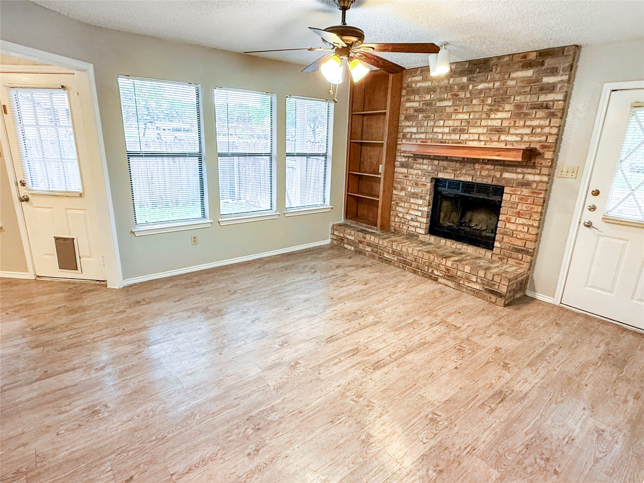 409 Rawhide Loop Round Rock, TX 78681 - Photo 5 of 14 Spacious interior featuring wood-finish flooring, a brick fireplace with a wood mantle, and an integrated wood bookcase