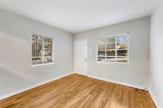 a view of an empty room with wooden floor and a window