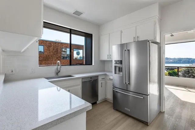 a kitchen with stainless steel appliances a refrigerator sink and wooden floor
