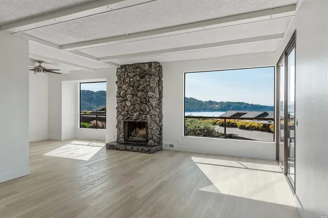 an empty room with floor to ceiling windows and fireplace