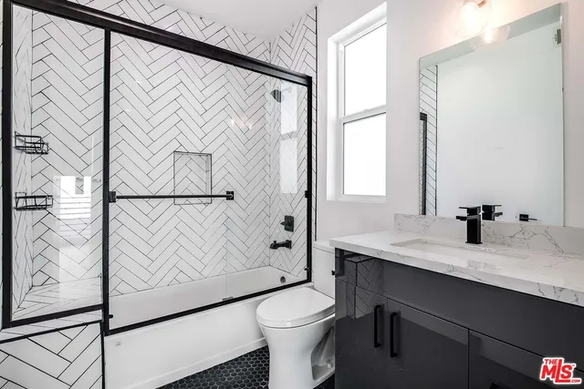 a bathroom with a granite countertop sink mirror vanity and toilet