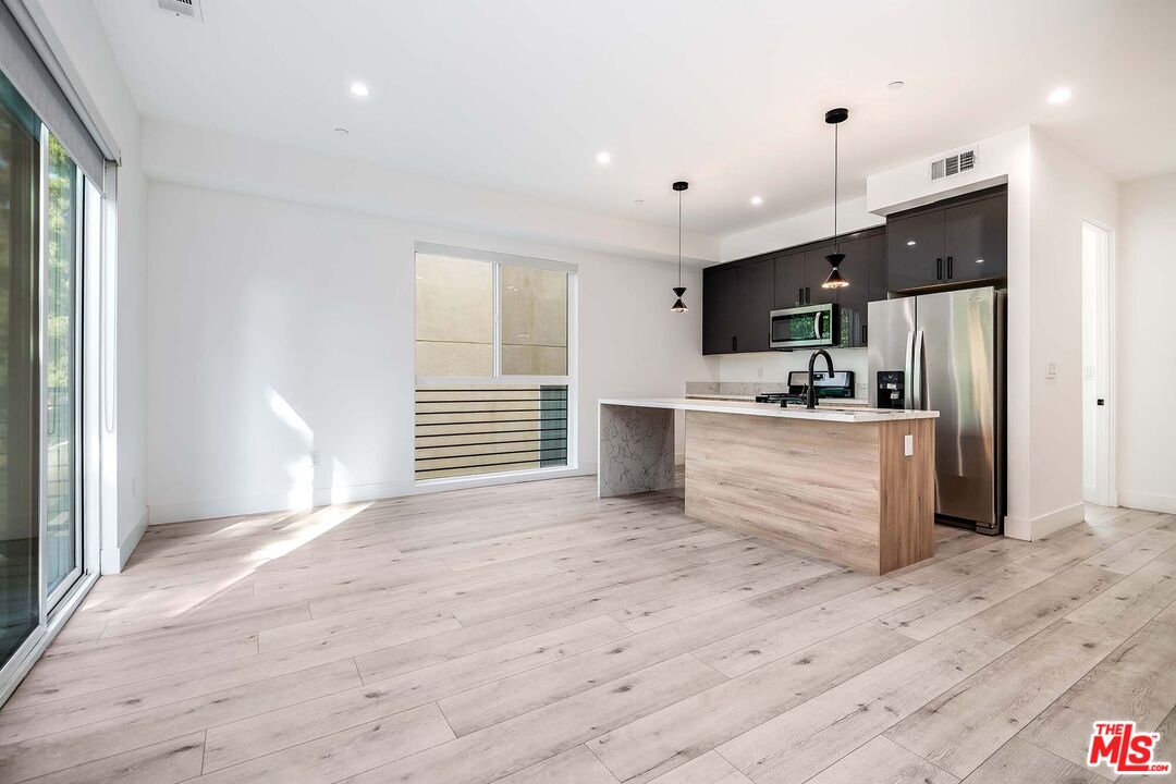 15330 Weddington Street Sherman Oaks, CA 91411 - Photo 5 of 30 a kitchen with stainless steel appliances kitchen island a refrigerator sink and cabinets