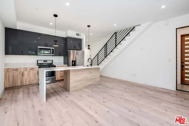 a kitchen with stainless steel appliances kitchen island wooden floors and white cabinets