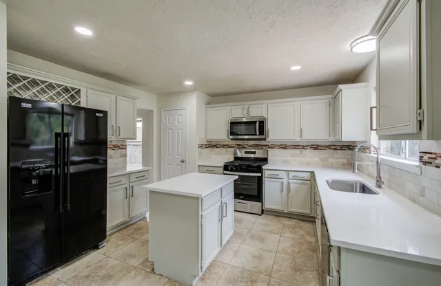 a kitchen with a sink white cabinets and stainless steel appliances