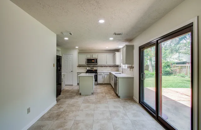 a large kitchen with a lot of white cabinets and stainless steel appliances