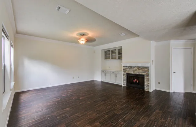 an empty room with wooden floor a fireplace and windows