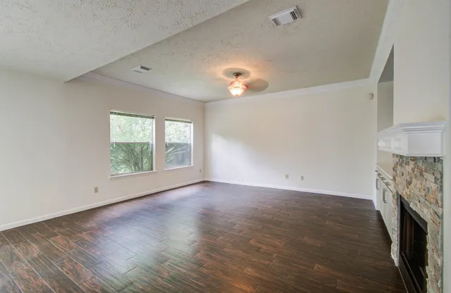 an empty room with windows fireplace and wooden floor