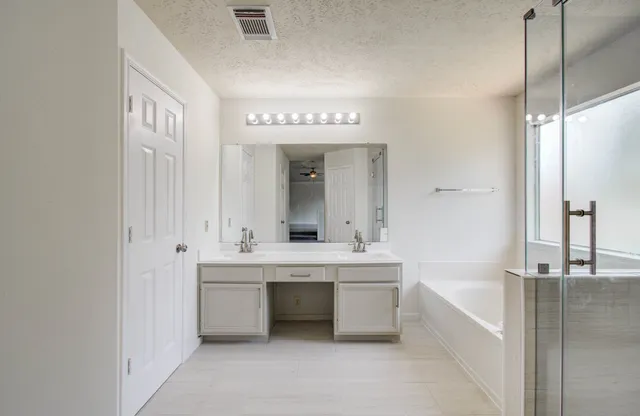 a spacious bathroom with a double vanity sink a mirror and a bathtub