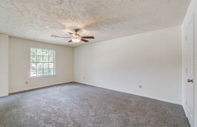 an empty room with windows and chandelier fan